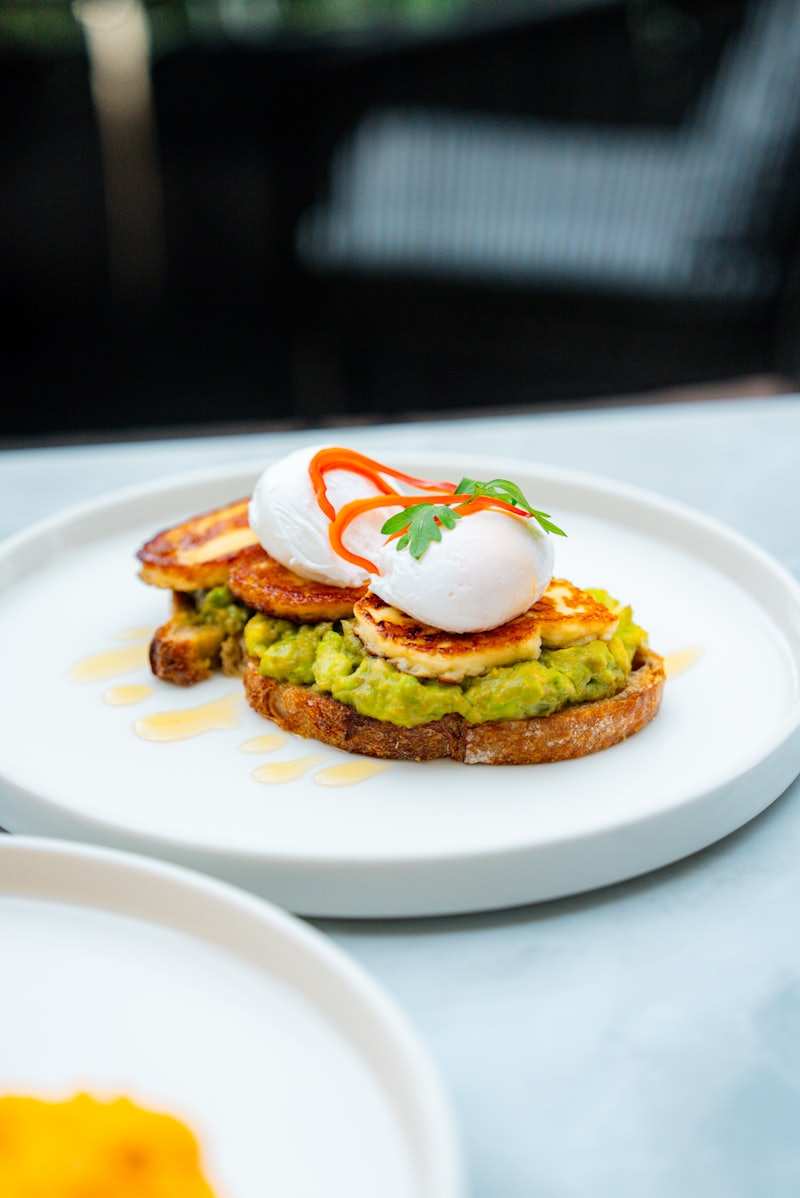 Two slices of avocado toast topped with a poached egg